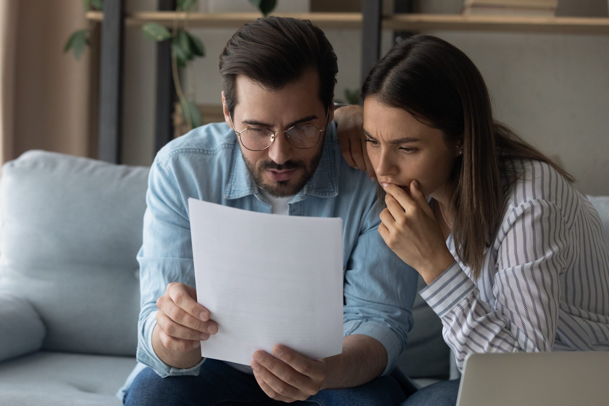 Close up puzzled focused couple reading letter together, bad news