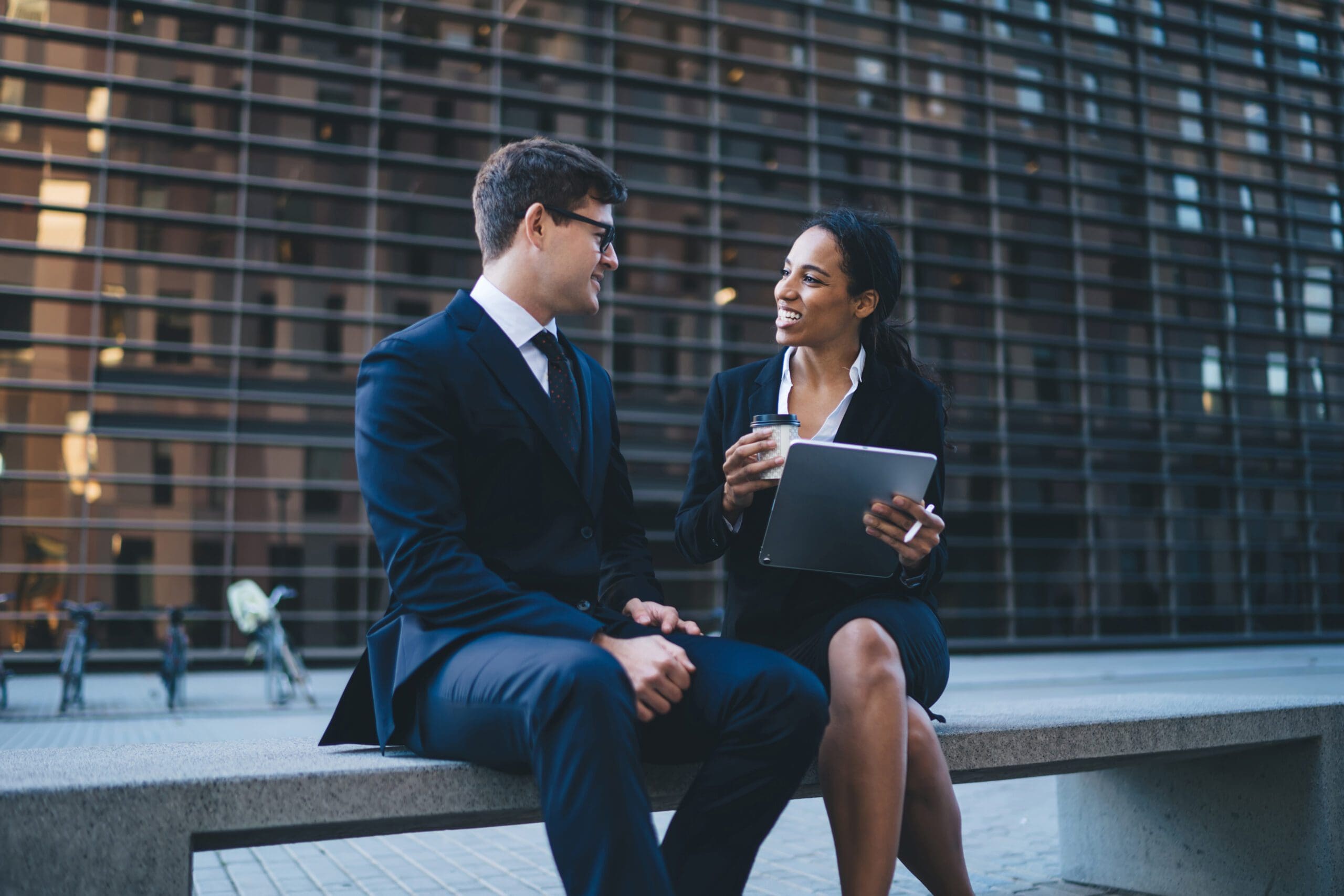 Cheerful colleagues having meeting on bench and talking